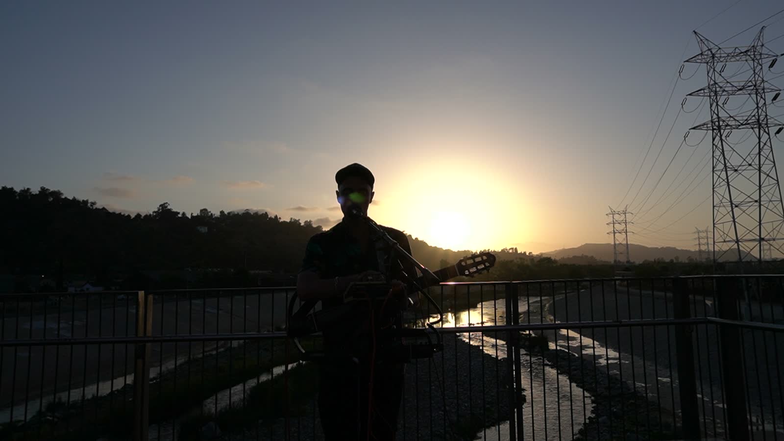 The sun touches the horizon behind the artist, the channel reflects the light.