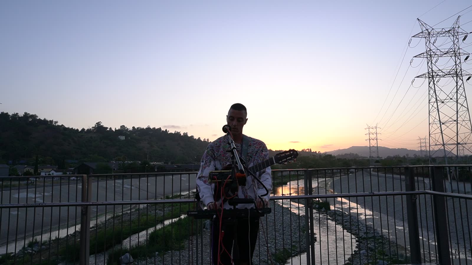 Purple sky after sunset, the artist sings at the microphone on the bridge, light patterned jacket.